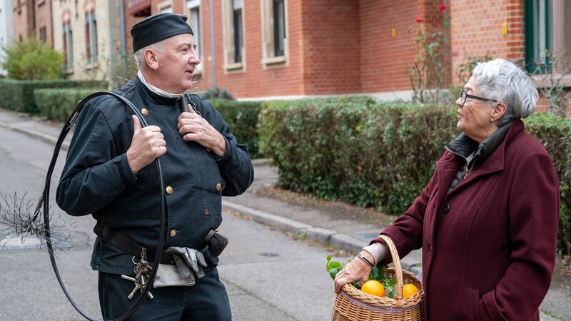 Der Bezirksschornsteinfeger Thomas Brändle (Bernd Kaczmarek, l.) war bei Anwohnern (Komparsin) und Kollegen beliebt und gern gesehen. Als er jedoch nach einem Sturz vom Dach tot aufgefunden wird, ist schnell klar: Das war kein Unfall. – Bild: ZDF und MARKUS_FENCHEL