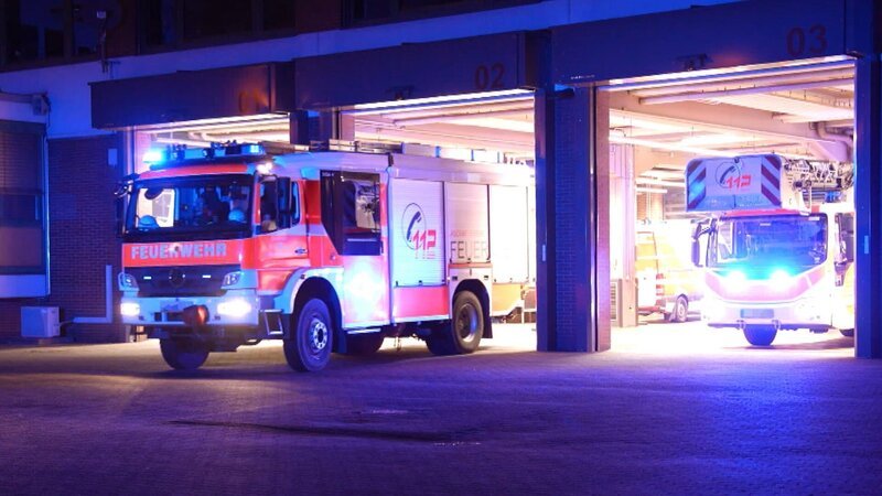Fire truck and turntable ladder from Aschaffenburg leave the hall at night. – Bild: Warner Bros. Discovery, Inc. or its subsidiaries and affiliates