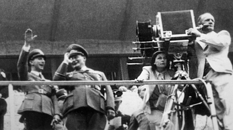 Leni Riefenstahl bei der Kamera, während der Dreharbeiten von „Olympia“ mit Joseph Goebbels und Hermann Göring auf der Tribüne (1936) (aus dem Nachlass). – Bild: WDR/Vincent Productions Leni Riefenstahl bei der Kamera, während der Dreharbeiten von „Olympia“ mit Joseph Goebbels und Hermann Göring auf der Tribüne (1936) (aus dem Nachlass). – Bild: WDR/Vincent Productions