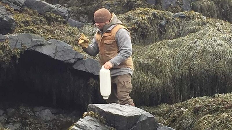 Bill McConnell on a rocky shore with a buoy and work gloves on Maine. – Bild: Discovery Communications