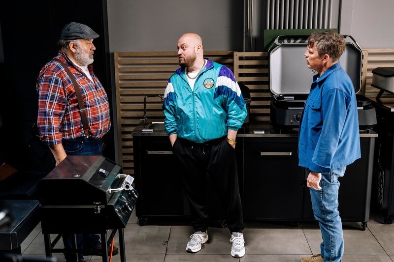 Kommissar Matti Wagner (Pierre Besson, r.) unterbricht den Grillfachmarkt-Geschäftsführer Stefan Ständler (Waldemar Kobus, l.) während eines vermeintlichen Verkaufsgesprächs mit Ronny Gilles (Baris Ar, M.). – Bild: ZDF und Martin Rottenkolber