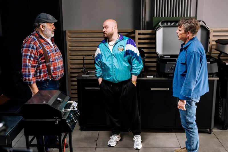 Kommissar Matti Wagner (Pierre Besson, r.) unterbricht den Grillfachmarkt-Geschäftsführer Stefan Ständler (Waldemar Kobus, l.) während eines vermeintlichen Verkaufsgesprächs mit Ronny Gilles (Baris Ar, M.). – Bild: ZDF und Martin Rottenkolber
