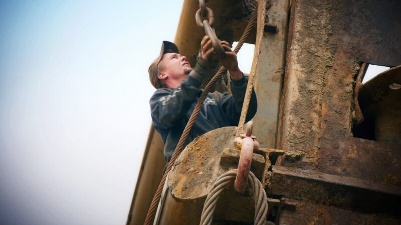 Arbeiter an der Maschine. – Bild: Warner Bros. Discovery