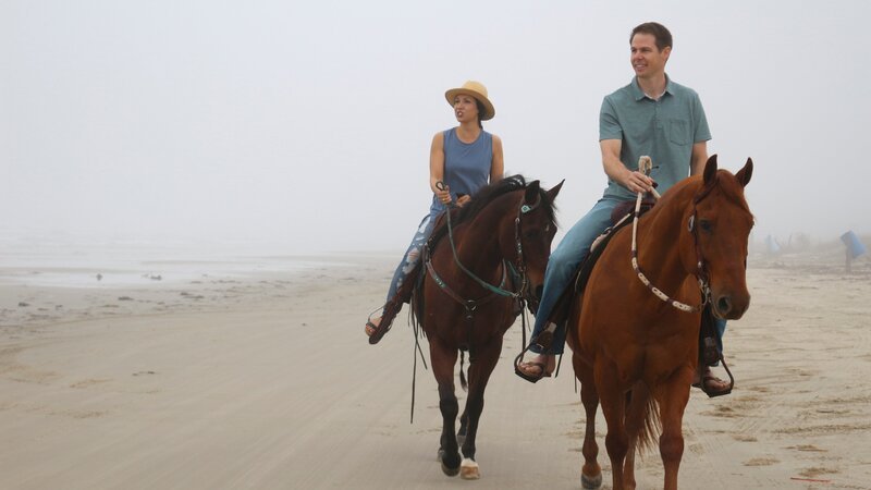 Contributors Laura Kasper (L) and Craig Kasper (R) enjoy horseback riding on the beach in Surfside Beach, Texas, as seen on HGTV’s Beachfront Bargain Hunt. – Bild: Discovery, Inc.