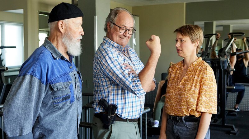 Vicky (Katja Danowski, r.) soll Klaus’ (Hartmut Volle, M.) Bizeps fühlen (mit Bill Mockridge, l.). – Bild: ARD/​Kai Schulz