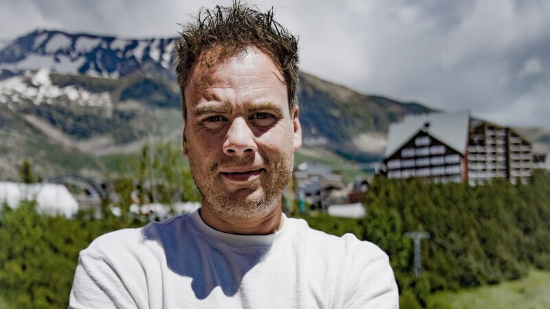 Ep8 – Sebastian with mountain in background, arms folded, medium shot – Bild: Warner Bros. Discovery, Inc. or its subsidiaries and affiliates