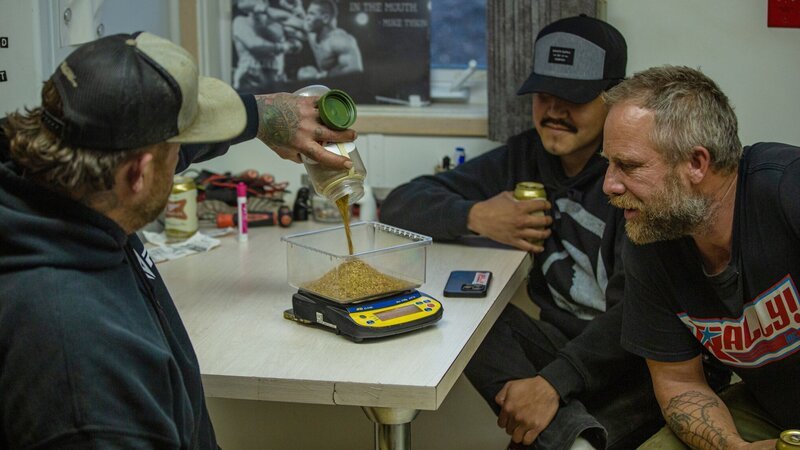 Rick Ness (l.) gießt Gold auf der Goldwaage, während Buzz Legault (r.) und Trey Charlie (2.v.r.) zusehen. – Bild: Warner Bros. Discovery, Inc.