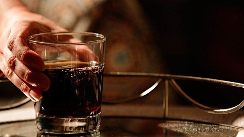 Eine Hand hält ein Glas auf dem Tisch – Bild: ZLW-S2-blackwatch /​ © Crime + Investigation