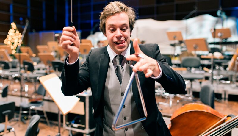 Checker Tobi spielt Triangel beim Münchner Rundfunkorchester. – Bild: BR/​megaherz gmbh/​Hans-Florian Hopfner