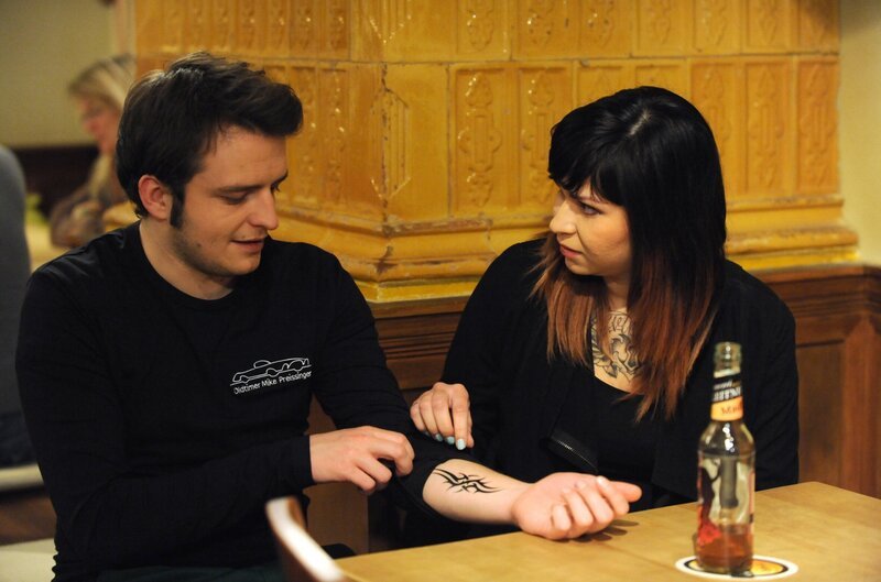 Flori (Tommy Schwimmer) versucht, seine neue Flamme (Mila Girsig) mit seinem Tattoo zu beeindrucken. – Bild: BR/​Marco Orlando Pichler