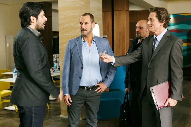 Maximilian (Francisco Medina, l.) überspielt seine Anspannung, als in Gegenwart von Richard (Silvan-Pierre Leirich, 2.v.l.) plötzlich der Zoll (r. Andreas Kunz, 2.v.r. Komparse) vor ihm steht. – Bild: RTL /​ Kai Schulz