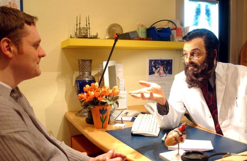 Dr. Rashad (Kaya Yanar, r.) behandelt einen Patienten. – Bild: SAT.1 /​ Ralf Jürgens Eigenproduktionsbild frei