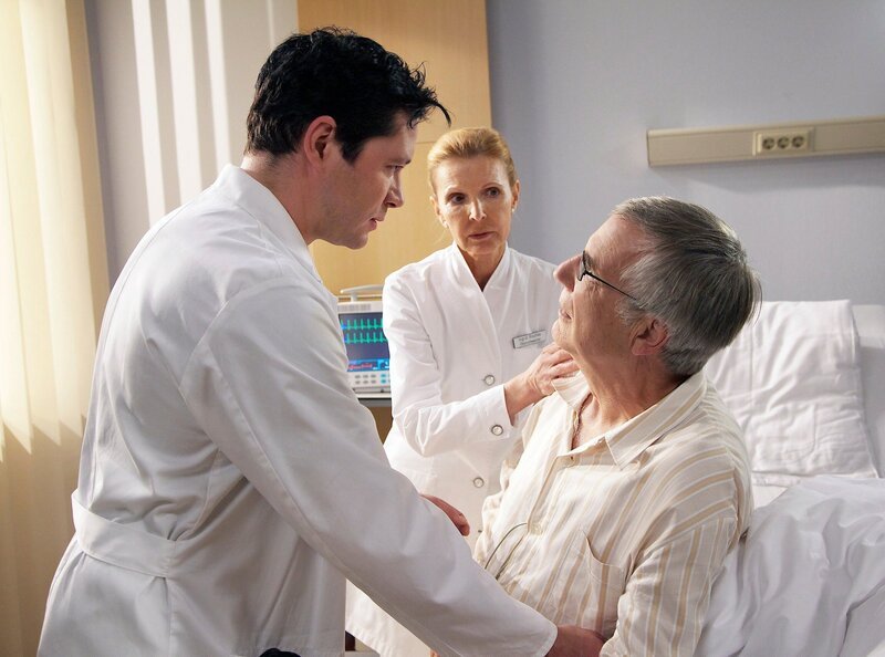 Im Gegensatz zu Prof. Simoni, vermutet Dr. Philipp Brentano (Thomas Koch, links) eine harmlosere neurologische Ursache für Waldners Zustand, als einen Schlaganfall. Doch plötzlich ruft Oberschwester Ingrid (Jutta Kammann, Mitte) aus Waldners Patientenzimmer um Hilfe. Nun hat Anton Waldner (Hubert Mulzer) auch im Bein Ausfallerscheinungen. Dies widerlegt Brentanos These und veranlasst Simoni dazu, an der Sorgfalt des jungen Arztes zu zweifeln. Brentano steht nach seiner Aufputschmittelsucht immer noch unter strenger Beobachtung seiner Kollegen. – Bild: MDR/​Wernicke