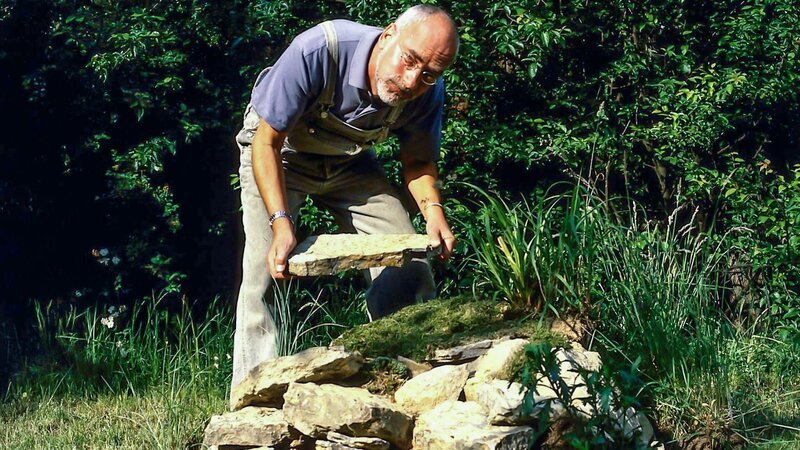 Peter (Peter Lustig) baut einen Eidechsenhügel in seinem Garten. Er ist gespannt, wann die ersten Drachenbabys bei ihm einziehen. – Bild: ZDF