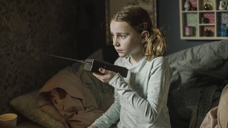 Rita (Selma Kjær Kuscu) steht Schmiere und hält Kontakt über ein Funkgerät. – Bild: BR/​TV 2 Denmark, Cosmo Film/​Balthazar Hertel