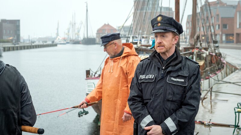 Timmermann (Mathias Junge, r.) treibt es zum Wismarer Hafen. Dort will er das Alibi von Hagen Franke, dem streitsüchtigen Nachbarn des Reiterhofs, überprüfen. Doch wie sich herausstellt, hat Hagen Franke gelogen. Er ist am Morgen nicht, wie behauptet, beim Angeln gewesen. Was hat er stattdessen gemacht? Hat er etwa das Drahtseil im Wald gespannt, um Gerald von Gungelitz umzubringen? – Bild: Marc Meyerbröker /​ ZDF