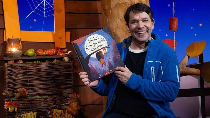 Juri stellt das Buch „Ich bin doch gar nicht gruselig!“ passend zum bundesweiten Vorlesetag vor. Darin geht es um die Fledermaus Fredo, die Freunde finden möchte. – Bild: KiKA