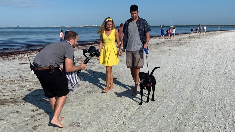 The crew (L) films contributors Tara Acree (C) and Michael Mills (R) walking their dog Biggie on a beautiful day as seen on HGTV’s Beachfront Bargain Hunt. – Bild: Discovery, Inc. All Rights Reserved.