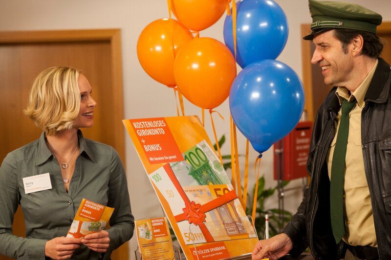 ARD HEITER BIS TÖDLICH – HUBERT UND STALLER FOLGE 32, „Schwarzer Freitag“ (Wh.), am Mittwoch um 18:50 Uhr im ERSTEN. Staller (Helmfried von Lüttichau, r.) lässt sich von der attraktiven Bankangestellten Betty (Jenny Marie Muck, r.), in einem Nebenzimmer der Bank beraten. – Bild: ARD/​TMG/​Chris Hirschhäuser