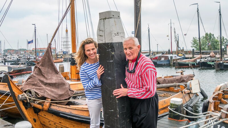 Moderatorin Andrea Grießmann mit Guide und ehemaligen Fischer Jan van Urk im Hafen der Ortschaft Urk auf Flevoland. Der Ort Urk war vor der Einpolderung eine Insel. – Bild: WDR/​Sabine Fricke