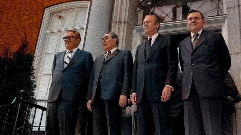 Ein historisches Gipfeltreffen inmitten des Kalten Krieges: Die KSZE veränderte letztlich die Welt. Anhand von Archivmaterial und nun freigegebenen Gesprächsprotokollen erweckt der Dokumentarfilm das politische Schachspiel von 1975 wieder zum Leben. Humorvolle und scharfsinnige Beobachtung der langsam mahlenden Mühlen der Diplomatie. Erzählt von Bjarne Mädel. – Henry Kissinger, Leonid Breschnew, Präsident Gerald Ford und Andrei Gromyko vor der US-Botschaft in Helsinki (30. Juli 1975) – Bild: rbb/​David Hume Kennerly/​The Gerald Ford Library & Museum