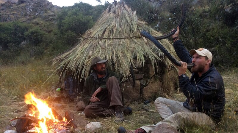 Feuer brennt, während Josh James (l.) Grady Powell (r.) beim Trinken aus dem Reifen zusieht. – Bild: Discovery Communications