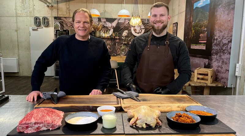 Spitzenkoch Björn Freitag (l.) und der Grill-Blogger und Unternehmer Joscha Bastians (r.) bereiten in dessen Grillschule Pulled Pork und Huhn für den Smoker vor. – Bild: WDR/​solis TV