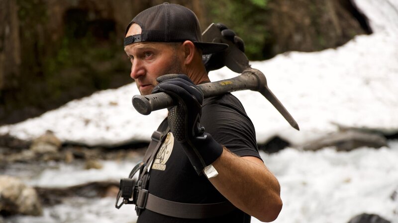 James Hamm holding a pickaxe looking off into the distance whilst working on removing the ice bridge – Bild: Warner Bros. Discovery, Inc. or its subsidiaries and affiliates. All rights reserved.