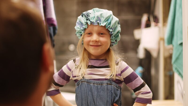 Vilda (Sofia Sittnikow) trägt vorsichtshalber eine Duschhaube, damit sie keinen ansteckt. – Bild: KiKA/​Anton Tevajärvi