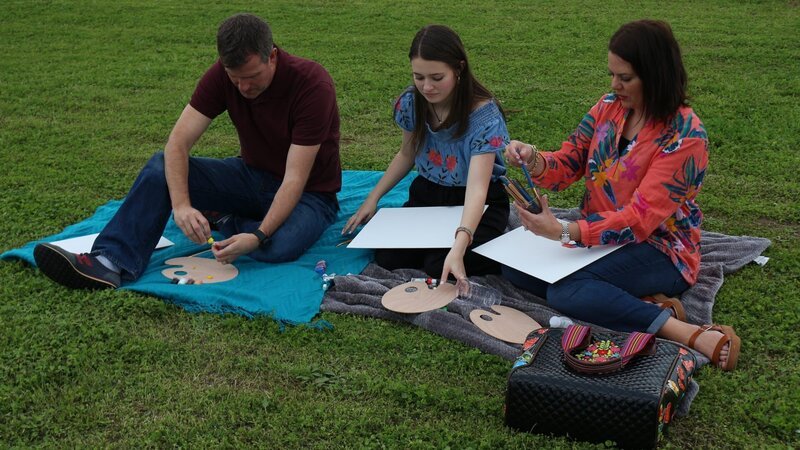 Contributors Julie Weldy (R) and Brett Weldy (L) enjoy an afternoon relaxing in the park and painting views of the water with their daughter Cady Weldy (C) as seen on HGTV’s Beachfront Bargain Hunt. – Bild: Discovery, Inc.