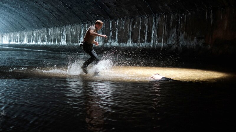 Was ist mit Haller (Philipp Hochmair, liegend)? Niko (Andreas Guenther) eilt seinem Chef zu Hilfe. – Bild: ARD Degeto/​Mona Film/​Tivoli Film/​Philipp Brozsek