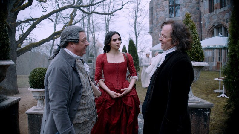 Leopold Mozart (Peter Kurth, l.) und Maria Anna Mozart (Havana Joy) treffen Dr. Wagner (Darius Petkevičius) vor der Klinik. – Bild: WDR/​Story House Pictures GmbH