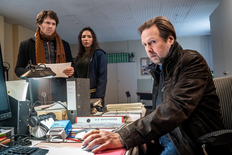 Tom Kowalski (Steffen Schroeder, l.) und Kim Nowak (Amy Mußul, M.) sprechen mit Armin Keil (Steffen Münster, r.) mit dem Arbeitskollegen des ermordeten Gerichtsvollziehers. – Bild: Uwe Frauendorf /​ ZDF Enterprises GmbH