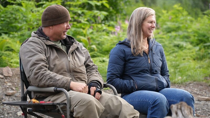 Dustin Hurt and Danielle Miller smiling sitting around the campfire. – Bild: Warner Bros. Discovery, Inc. or its subsidiaries and affiliates. All rights reserved.