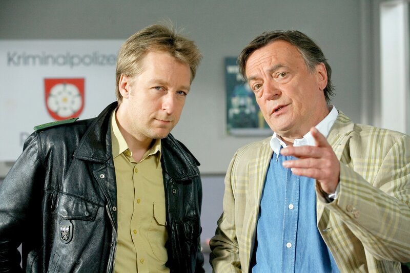 Polizist Michi Mohr (Max Müller, l.) ist sich sicher, dass der amerikanische Geschäftsmann Ross Keeler (Dietmar Mues) mit dem Mord zu tun hat. – Bild: ORF