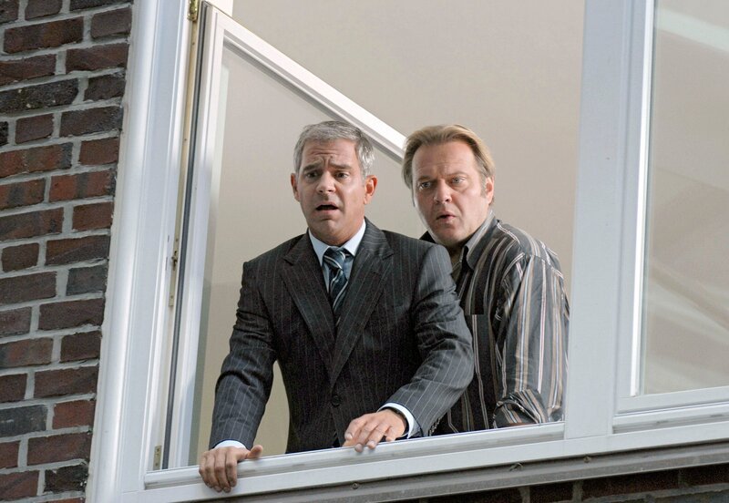 NDR Fernsehen ELVIS UND DER KOMMISSAR, „Kubanische Zigarren“, am Donnerstag (17.06.10) um 23:15 Uhr. Behringers Chef (Florian Fitz, l.) schaut entsetzt aus dem Fenster des Präsidiums, und der Kommissar (Jan-Gregor Kremp, r.) blickt ihm verblüfft über die Schulter: In Seibolds Dienstwagen ist eine Bombe explodiert. – Bild: NDR/​ARD/​Marion von der Mehden