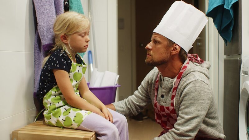 Papa (Peter Kanerva) tröstet Vilda (Sofia Sittnikow). Ihr ist ganz übel von dem vielen Lebkuchenteig. – Bild: KiKA/​Anton Tevajärvi
