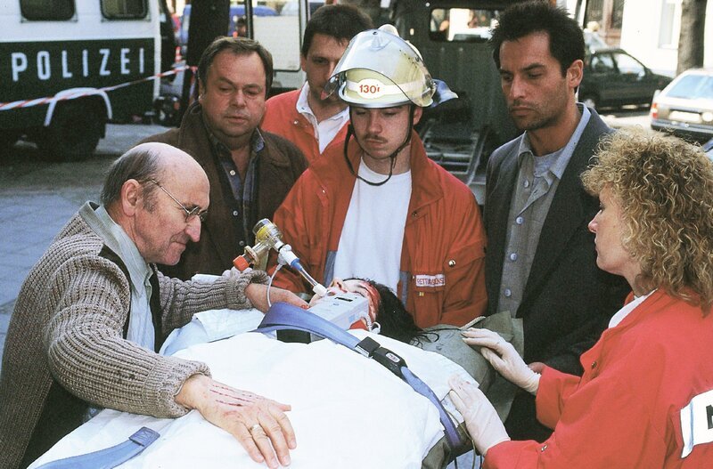 Horst Schneiders (Hannes Stelzer, li.) Tochter Sabine wird nach dem Sturz aus dem dritten Stock abtransportiert. Die Kommissare Kehler (Wolfgang Bathke, 2.v.li.) und Eschenbach (Matthias Bullach, 2.v.re.) hatten ihn benachrichtigt. – Bild: RTL