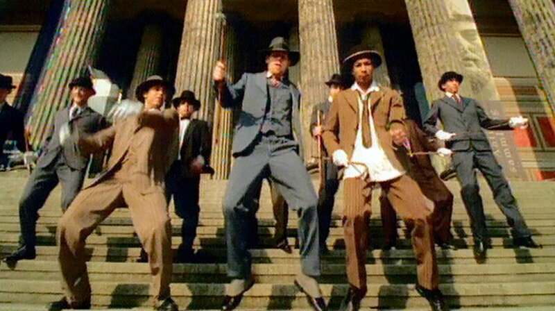 Das Jahr 2001 – die Terroranschläge des 11. September bringen auch das Berliner Leben zum Stillstand, Klaus Wowereit wird Regierender Bürgermeister und mit der Einweihung des neuen Bundeskanzleramts wird der Regierungsumzug nach Berlin abgeschlossen. Eine Berlin-Chronik der Superlative: Fünf Jahrzehnte von 1961, dem Jahr des Mauerbaus, bis 2009 als Berlin eine Weltstadt im 21. Jahrhundert ist. – Dickes B – Der Berliner Band SEEED gelingt der Hit des Jahres. – Bild: rbb