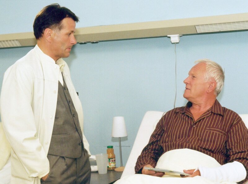 Dr. Heilmann (Thomas Rühmann, links) weiß, dass Paul Pigor (Alfred Müller) seinen Freund zu einer lebensrettenden OP überreden kann und bittet ihn um seine Hilfe. – Bild: MDR/​Krajewski