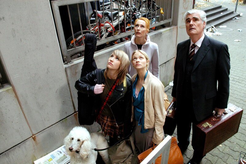 Sarah (Maxi Warwel), Lilo (Mavie Hörbiger) Adina (Andrea Sawatzki) und Paul Heinrich (Sky du Mont) gehen mit ihrem letzten Hab und Gut, ein paar exklusiven Taschen und Koffern, auf den tristen Hochhauseingang zu. Vanessa tippelt an der Leine mit. – Bild: ORF/​RTL