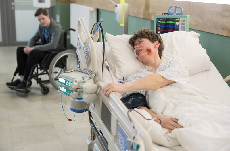 Cosmo Wolff (Max Bär, hinten) gibt sich die Schuld am Zustand seiner leiblichen Mutter. Hätten die beiden sich nicht mal wieder gestritten, wären sie möglicherweise nicht in den Massenunfall verwickelt worden. Doch plötzlich spricht ein weiterer schwerverletzter Patient (Juri Winkler, vorn) mit Cosmo. – Bild: MDR/​Rudolf Wernicke