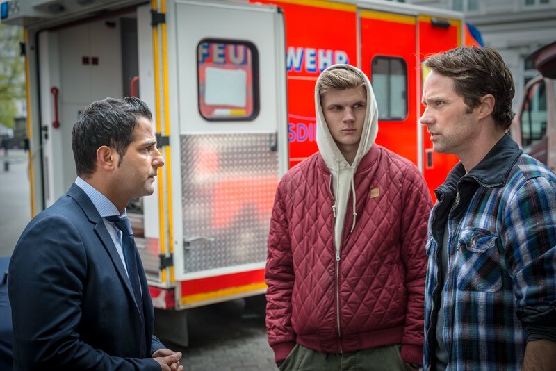 Tarik (Serhat Cokgezen, l.) und Mattes (Matthias Schloo, r.) befragen den Zeugen (Komparse), der die Polizistin im Müllcontainer gefunden hat. – Bild: ZDF/​Boris Laewen