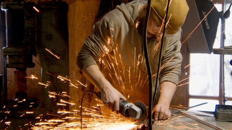 Da sprühen die Funken wie bei einer Wunderkerze. Jakob schneidet Stahl-Stücke, die dann zu einem Damastmesser verarbeitet werden sollen. – Bild: BR/​Markus Schindler/​Pius Neumaier