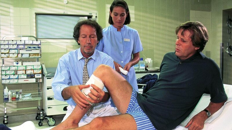 Dr. Ulrich Waldner (Hartmut Becker, l.) versorgt die Schusswunde von Dr. Stefan Frank (Sigmar Solbach). Eine Krankenschwester (Komparsin) assistiert. – Bild: MG RTL