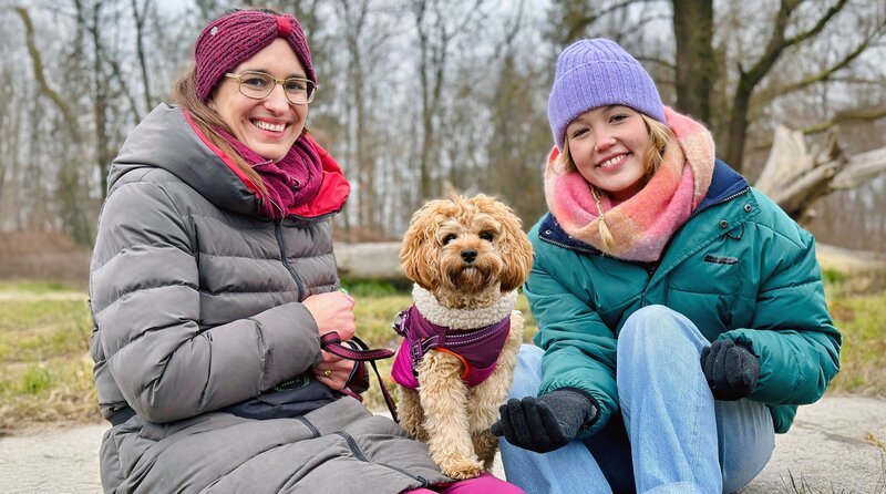 Hundetrainerin Leandra (links) zeigt Nina einen typischen Begleithund: Der kleine Cooper ist ein Cavapoo, eine Mischung aus Cavalier King Charles Spaniel und Pudel (Dr. Leandra Sabass). Weiteres Bildmaterial finden Sie unter www.br-foto.de. – Bild: BR/​Text und Bild Medienproduktion GmbH & Co. KG/​Katharina Brackmann