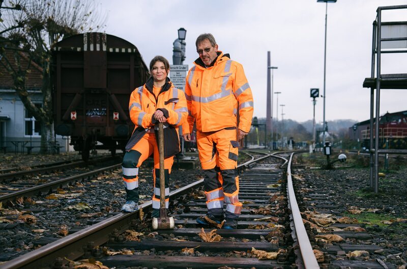 Sie sind Azubis und sie lieben ihren Job. Was wird sie diesmal auf den Baustellen erwarten? Oft wachsen die Auszubildenden über sich hinaus, manchmal geht auch alles schief. Zum Glück sind ihre Ausbilder, die Meister und Gesellen, eng an ihrer Seite. Und auch ihre Freunde und alle Familienmitglieder fiebern mit. – Azubine Burcu und Ausbilder Jürgen beim Gleisbau. – Bild: WDR/​Ben Knabe