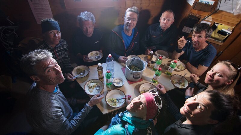 Die siebenköpfige Gruppe mit ihren beiden Bergführern in der Hütte. Das einfache Leben schweißt das Team zusammen. – Bild: ZDF und SRF/​Sam Gyger