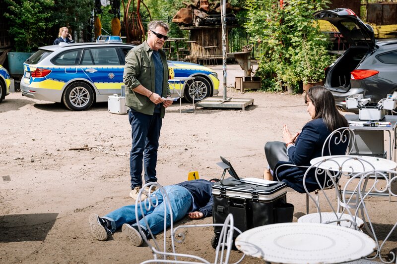 Dr. Pilar Westphal (Yulia Yáñez Schmidt, r.) erklärt Kommissar Matti Wagner (Pierre Besson, l.), dass der Amerikaner Steve Nolan (Eric Haarhaus, M.) durch Fremdeinwirkung ums Leben kam. – Bild: ZDF und Martin Rottenkolber