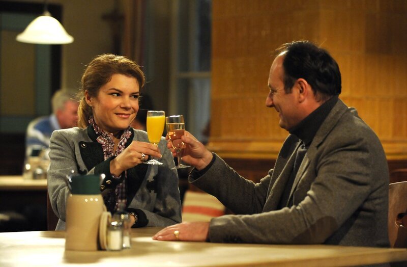 Uschi und Hubert stoßen zur Feier des Tages auf ihren Nachwuchs an. Von links: Uschi Guggenmoser (Silke Popp) und Hubert Kirchleitner (Bernhard Ulrich). – Bild: BR/​Marco Orlando Pichler